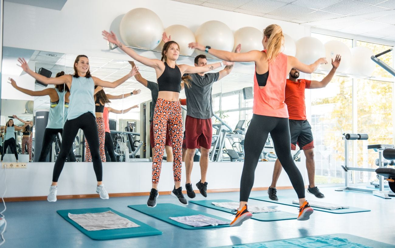 A personal trainer leading an energetic small-group workout in a bright gym